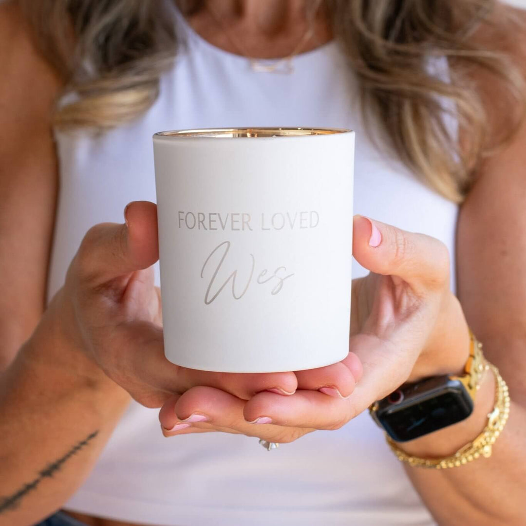 Forever Loved Custom Engraved Candle in white ceramic, engraved with 'FOREVER LOVED' and 'Wes,' held in hands.