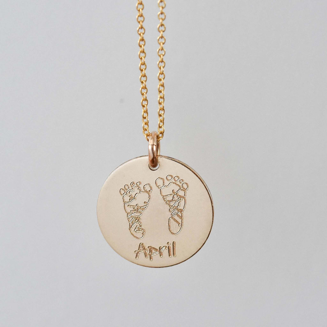 Custom Handprint or Footprint Necklace with engraved baby footprints and name 'April', gold charm on a delicate chain.