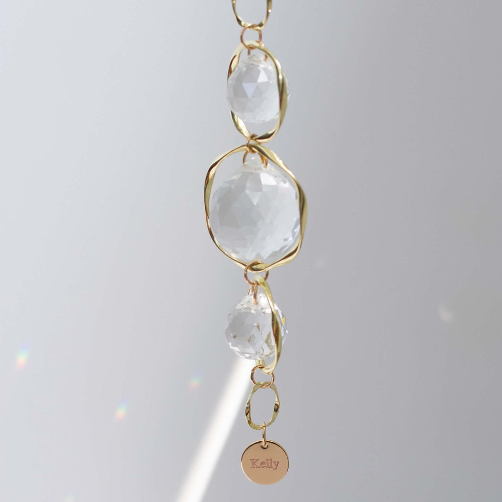 Light in Dark Places Gift Box features a clear crystal sun catcher with gold accents and a pink engraved charm reading 'Kelly'.