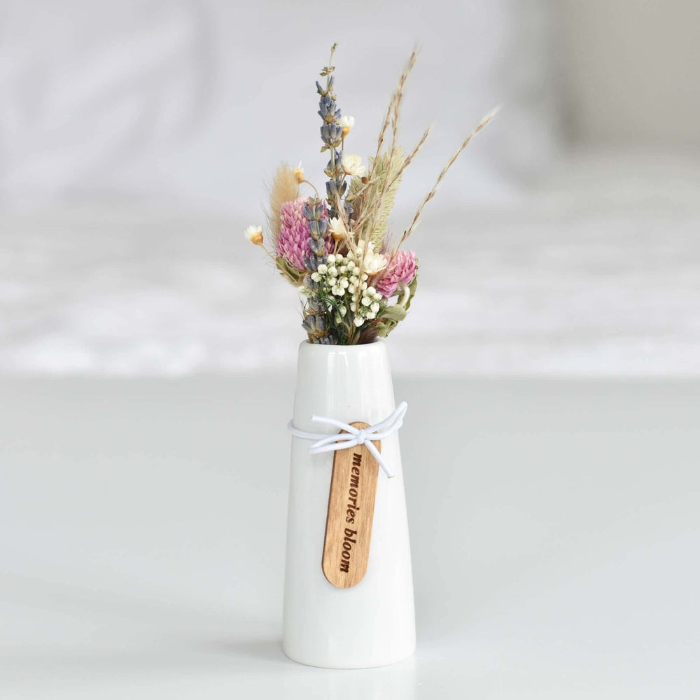 Memories Bloom Forever Dried Floral Bouquet in a white cone-shaped vase with dried flowers and a wooden tag.