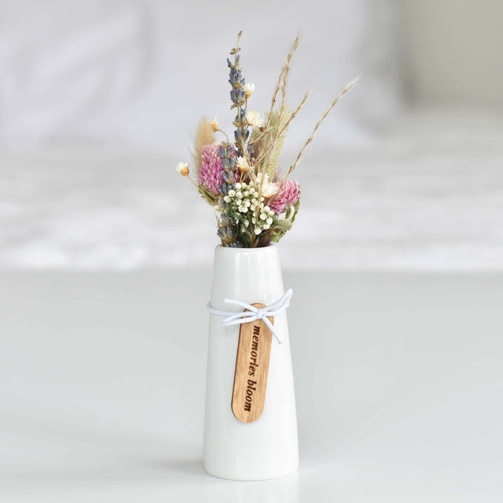 Memories Bloom Forever Dried Floral Bouquet in a white cone-shaped vase with dried flowers and a wooden tag.