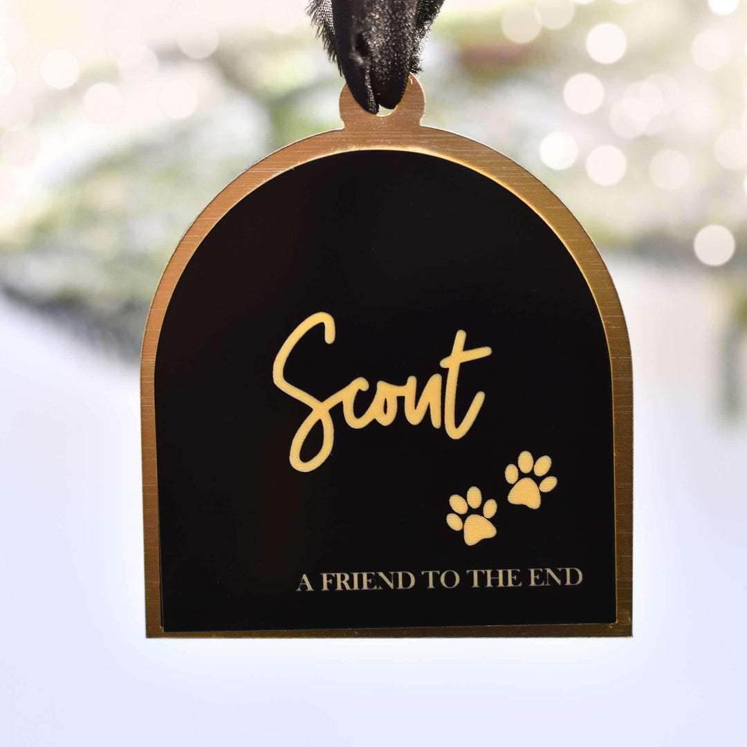 Friend to the End Pet Memorial Ornament, black acrylic with gold text 'Scout' and paw prints, arched shape with a black ribbon.