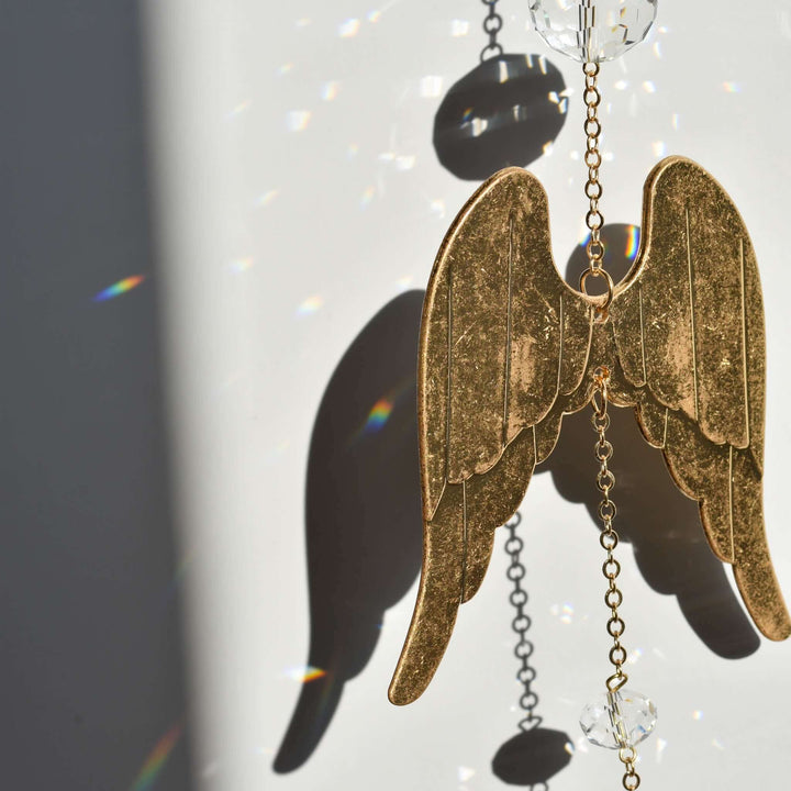 Angel Wing Sun Catcher &amp; Rainbow Maker, gold metal angel wings with crystal beads, casting colorful light patterns.