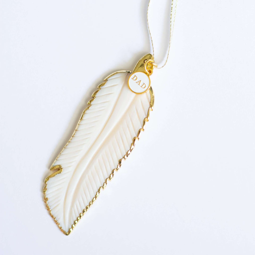 In Memory Feather Ornament, hand-carved white feather with gold trim and tag reading &