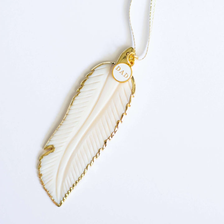 In Memory Feather Ornament, hand-carved white feather with gold trim and tag reading &