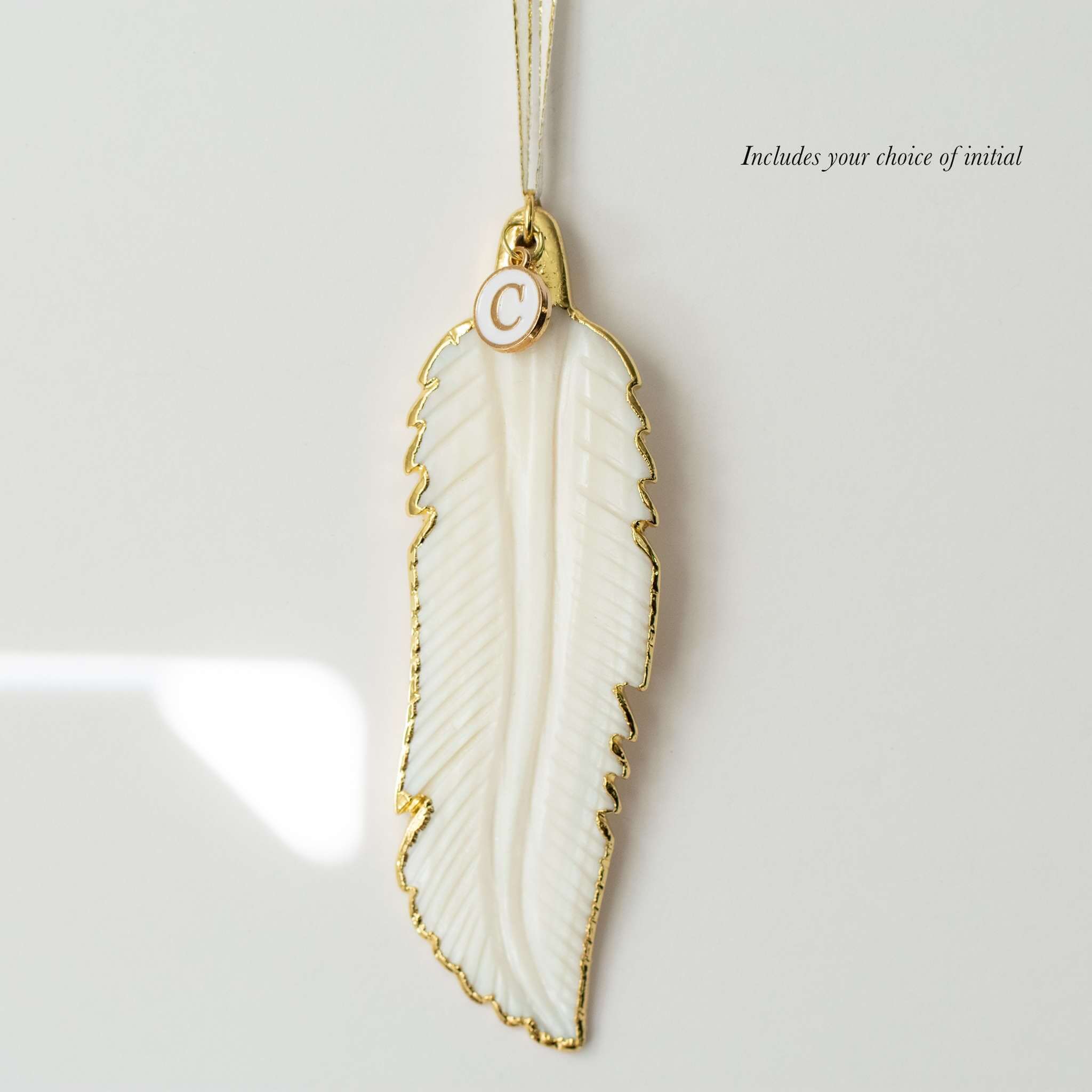 Sound of an Angel white leaf pendant with gold trim and a small initial tag attached, designed for remembrance gift.