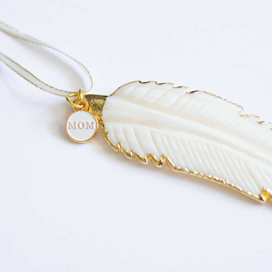 In Memory Feather Ornament, white hand-carved feather with gold trim, and a small round charm engraved &