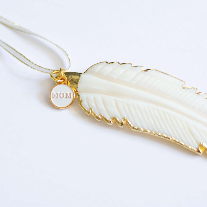 In Memory Feather Ornament, white hand-carved feather with gold trim, and a small round charm engraved &