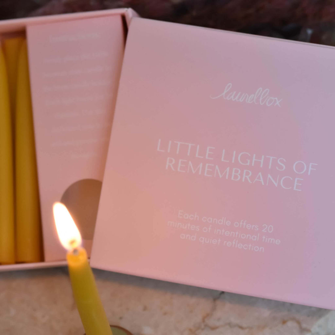 Little Lights of Remembrance candle set in a pink box, showcasing a lit yellow candle with text on packaging.