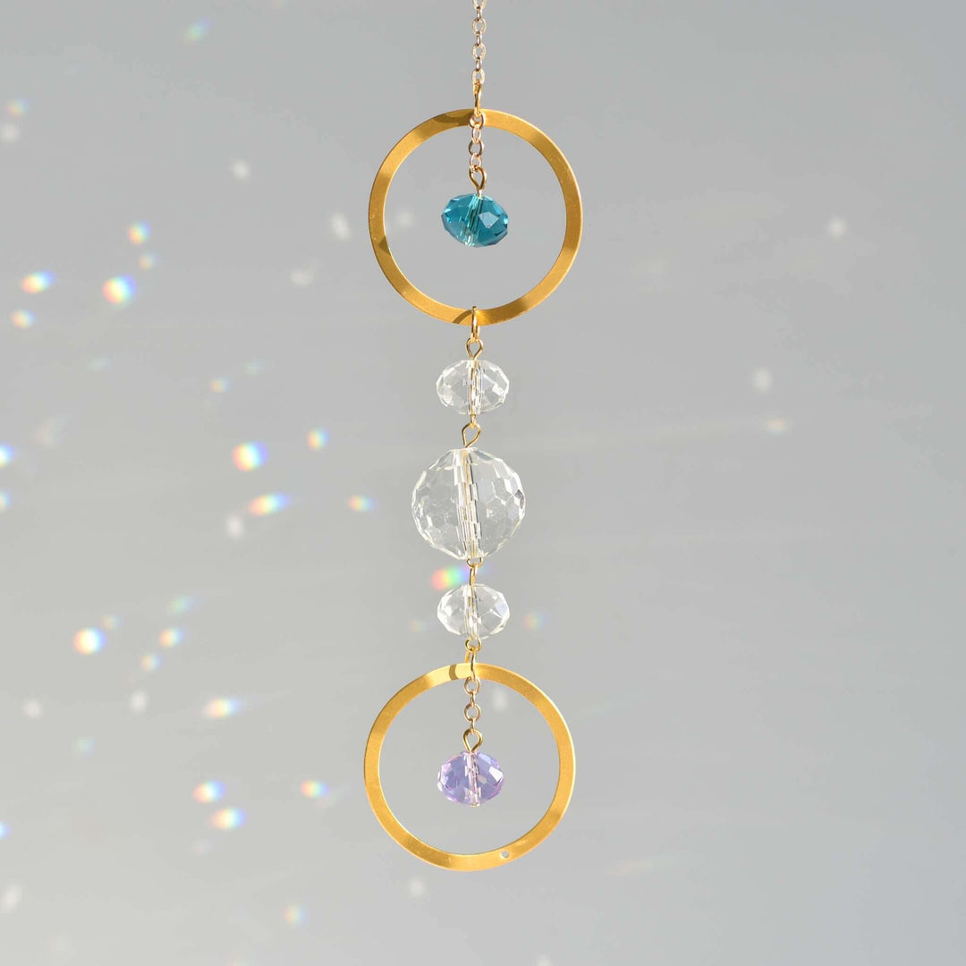 Memorial Birthstone Sun Catcher with gold rings and multicolored crystals, hanging against a light gray background.