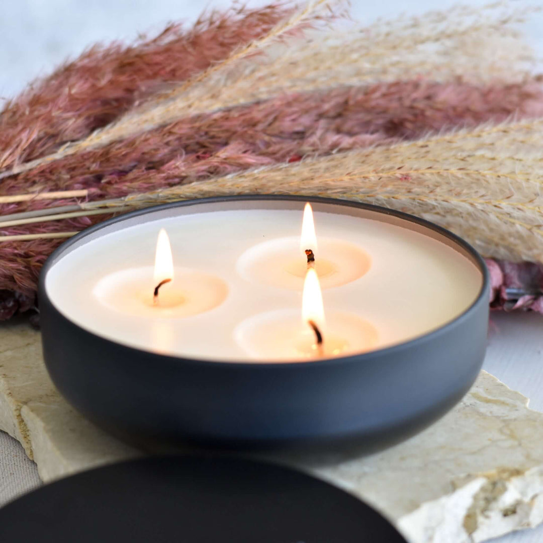 Morningside Employee Sympathy Gift includes a black bowl with three lit candles and pampas grass in the background.