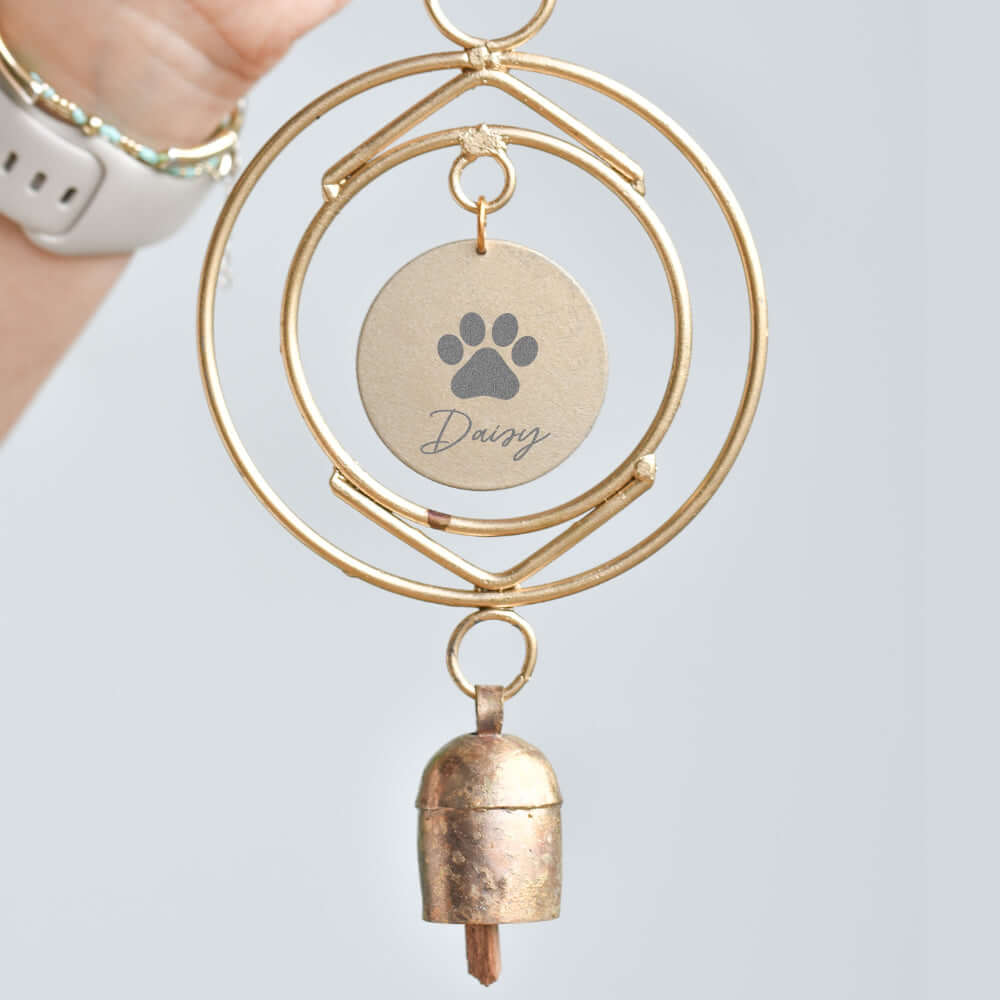 Dog Loss Wind Chime with gold circular frame, engraved tag reading 'Daisy' with a paw print, and a small bell.