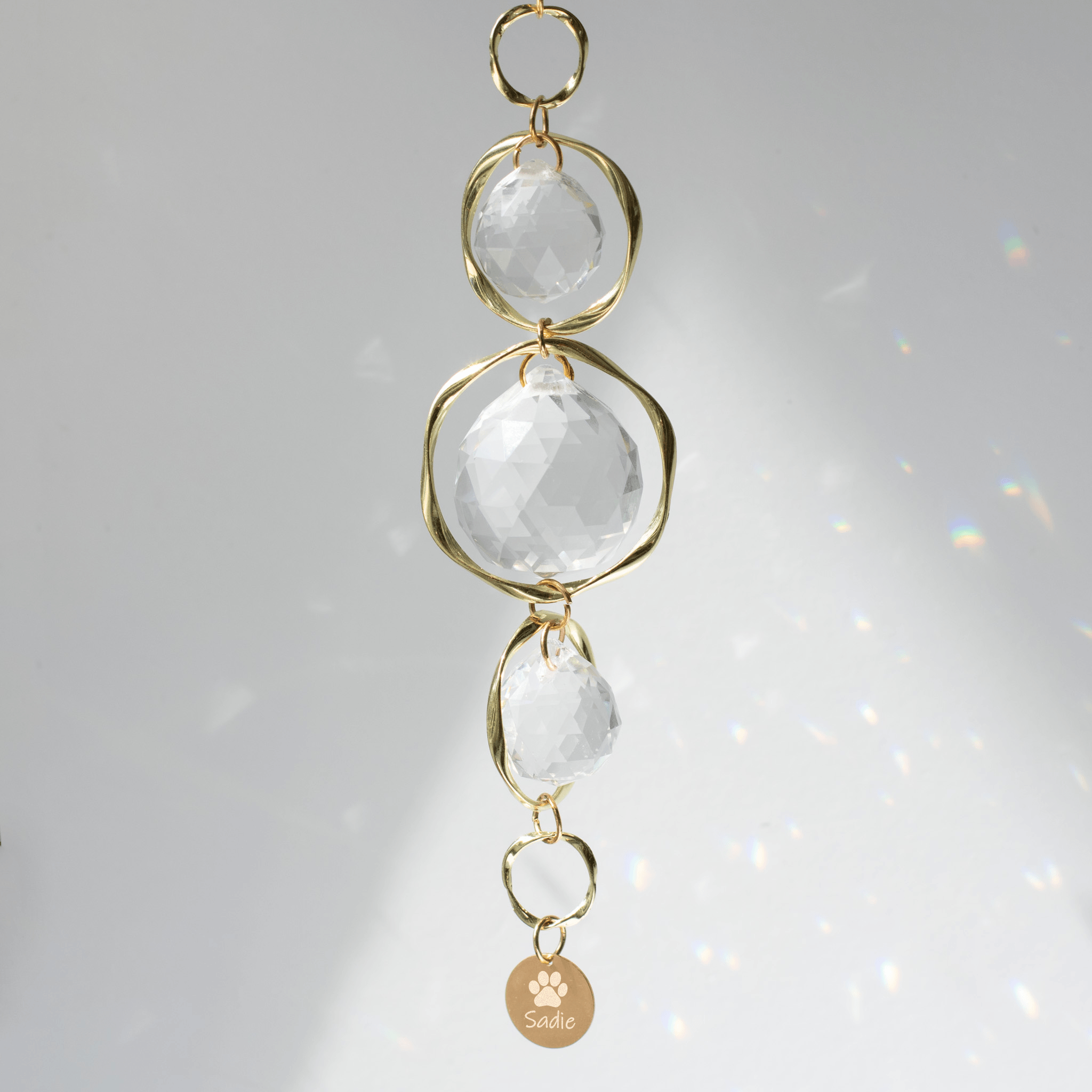 Pet Memorial Sun Catcher and Rainbow Maker with clear crystals, gold loops, and engraved tag saying 'Sadie'.