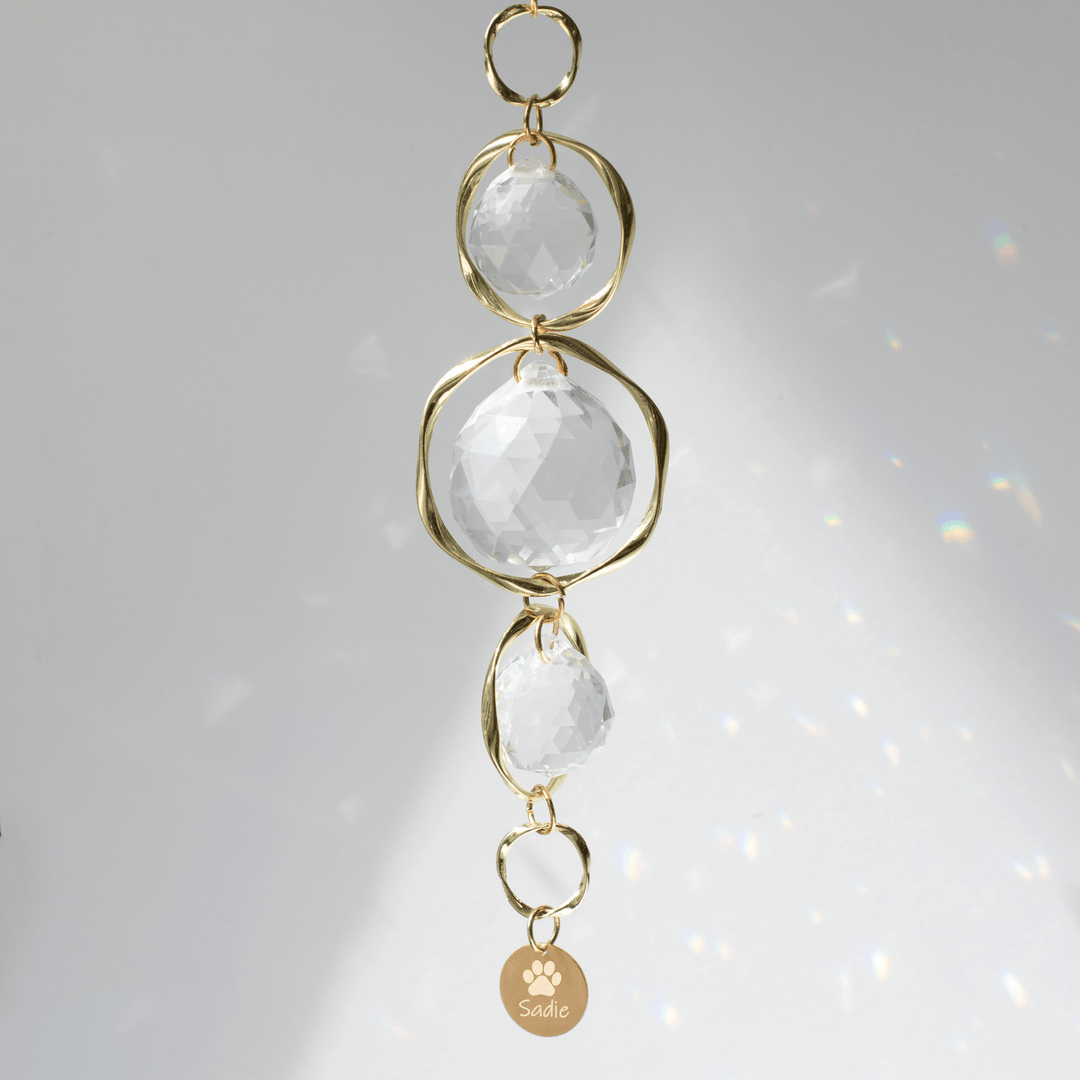 Pet Memorial Sun Catcher and Rainbow Maker with clear crystals, gold loops, and engraved tag saying 'Sadie'.