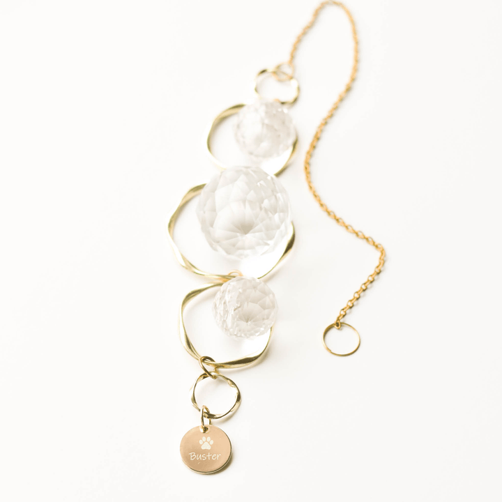 Pet Memorial Sun Catcher and Rainbow Maker with clear glass orbs and gold chain, engraved "Buster" with paw print charm.