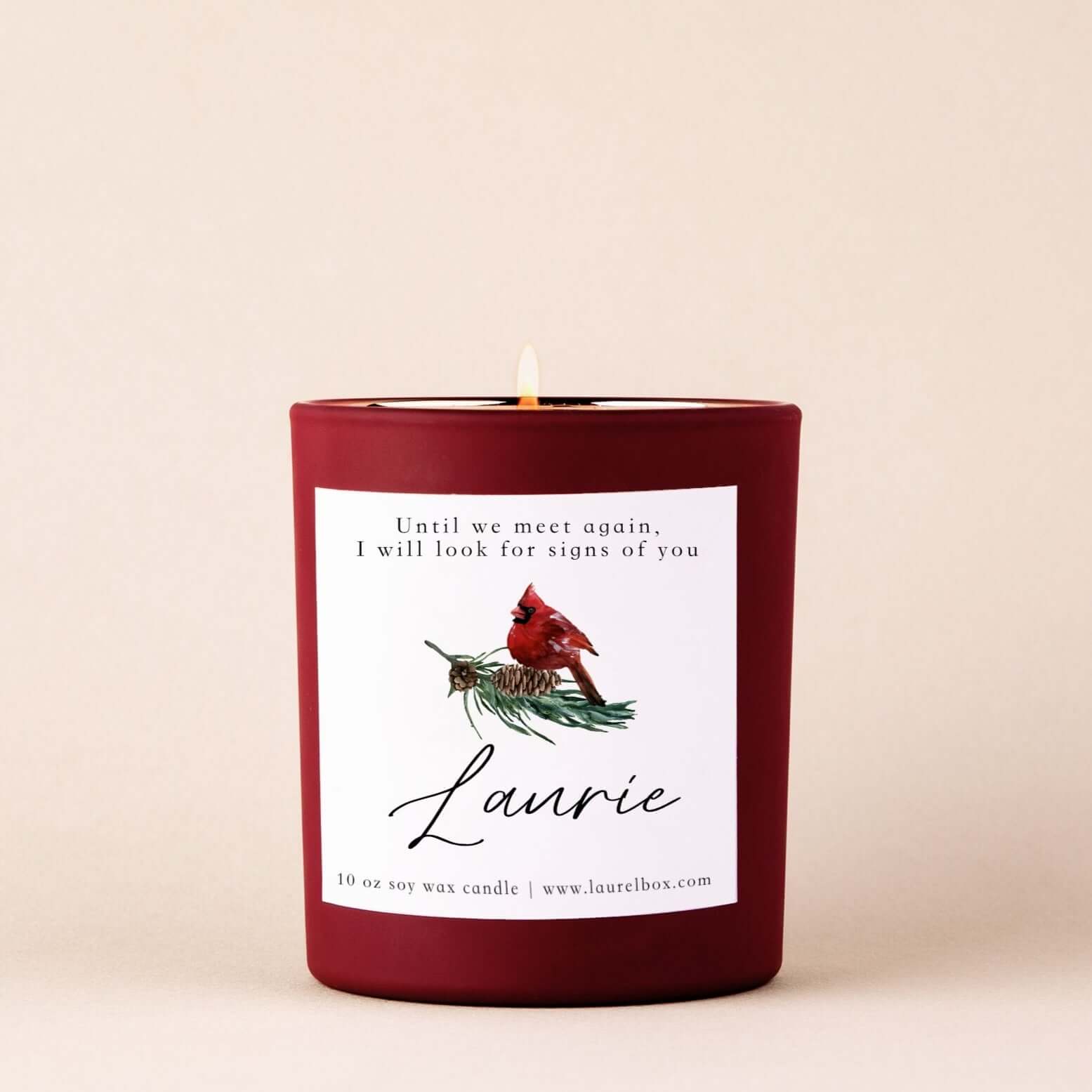 Red 10 oz soy wax candle with a cardinal design and text about looking for signs, labeled "Laurie".