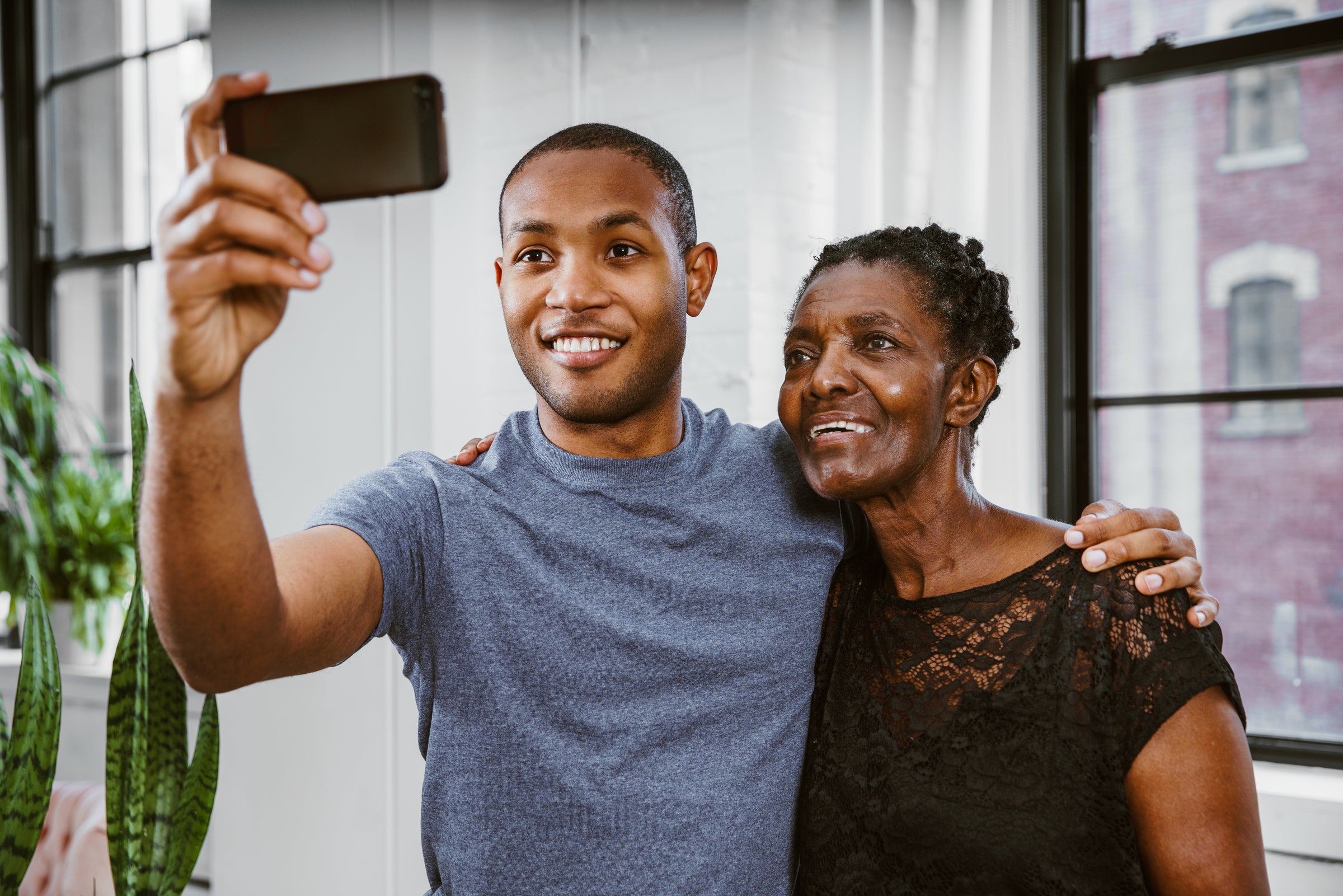 photo of a young man with his hand around an older woman’s shoulder taking a picture of the both of them