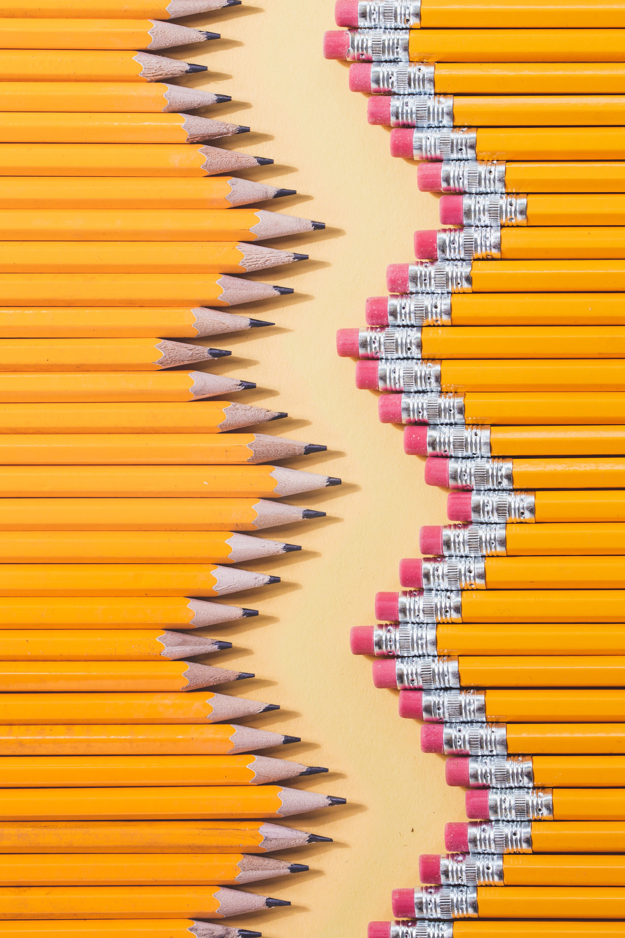 photo of a line of sharpened pencils pointing towards a line of the erasers of another line of pencils