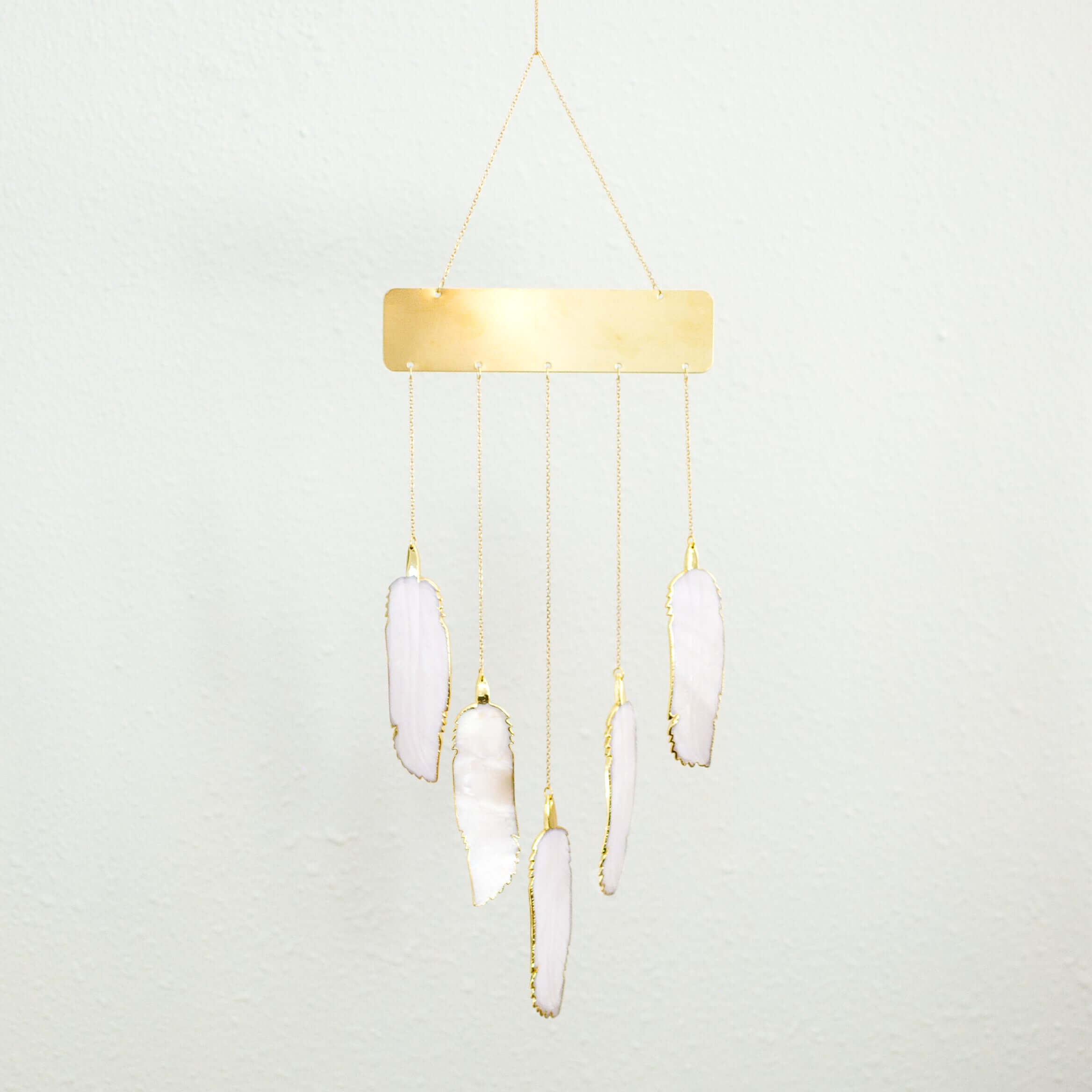 Loved & Remembered Memorial Chime made of brass and hand-carved mother of pearl feathers hanging, with gold accents.