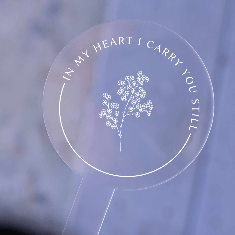 Miscarriage and Child Loss Garden Stake made of clear acrylic, featuring floral design and text reading 'IN MY HEART I CARRY YOU STILL'.