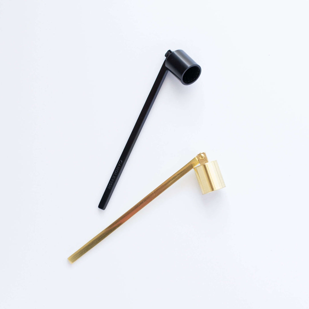 Candle Snuffer in brushed gold and matte black, long handles with cylindrical cups to extinguish candles.