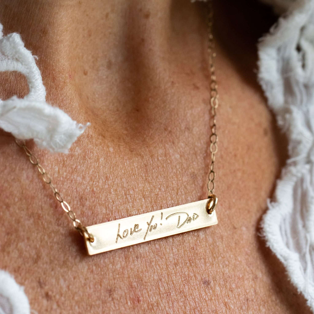 Custom Engraved Handwriting Necklace in gold, engraved with 'love you! Dad,' hanging on a delicate chain.