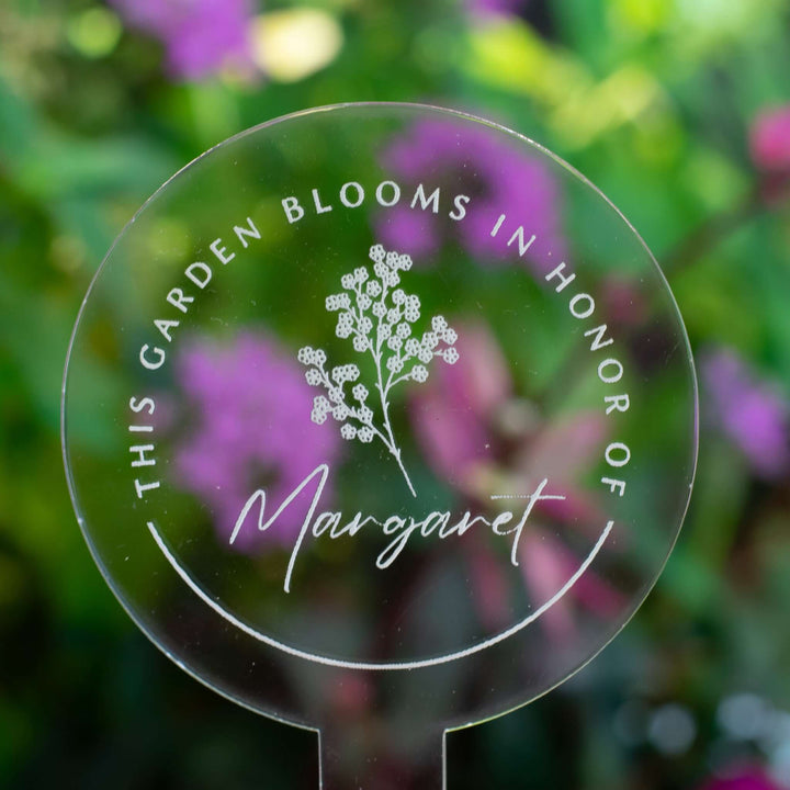 Custom Memorial Garden Stake made of clear acrylic with engraved text and design for Margaret, surrounded by flowers.