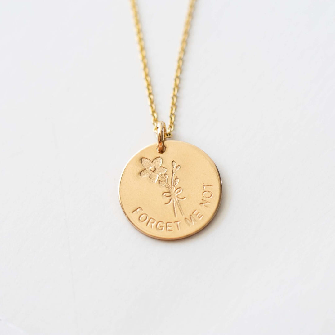 Forget Me Not Necklace with gold filled charm, featuring a flower design and engraved text on a delicate chain.