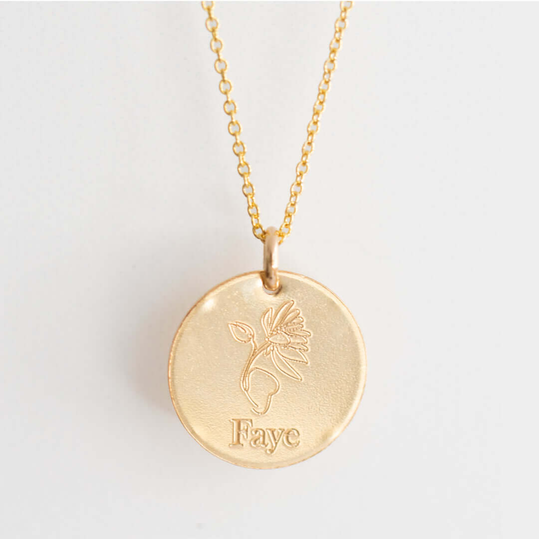 Birth Flower Necklace with a gold-filled chain and a round charm engraved with a flower and the name 'Faye', 16mm diameter.