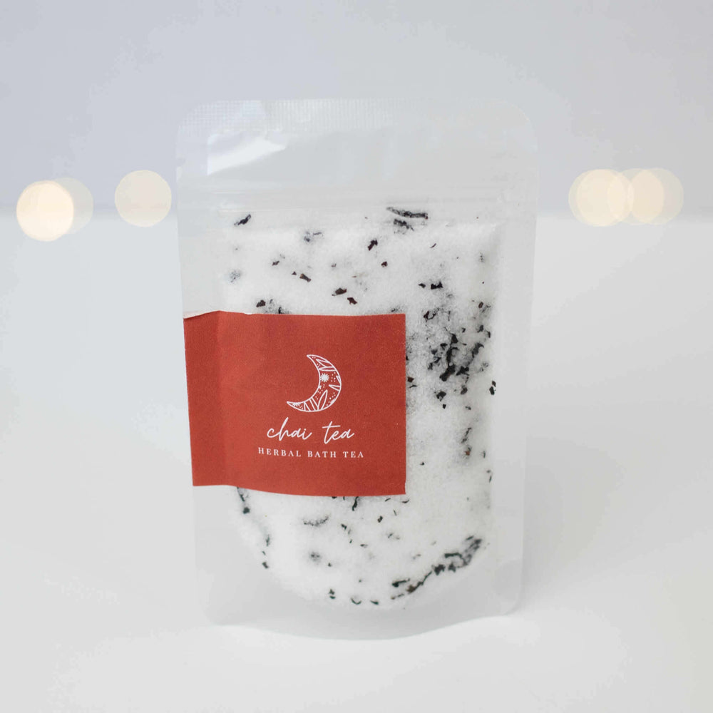 A transparent pouch filled with white herbal bath tea; red label says 'chai tea' and 'HERBAL BATH TEA'.