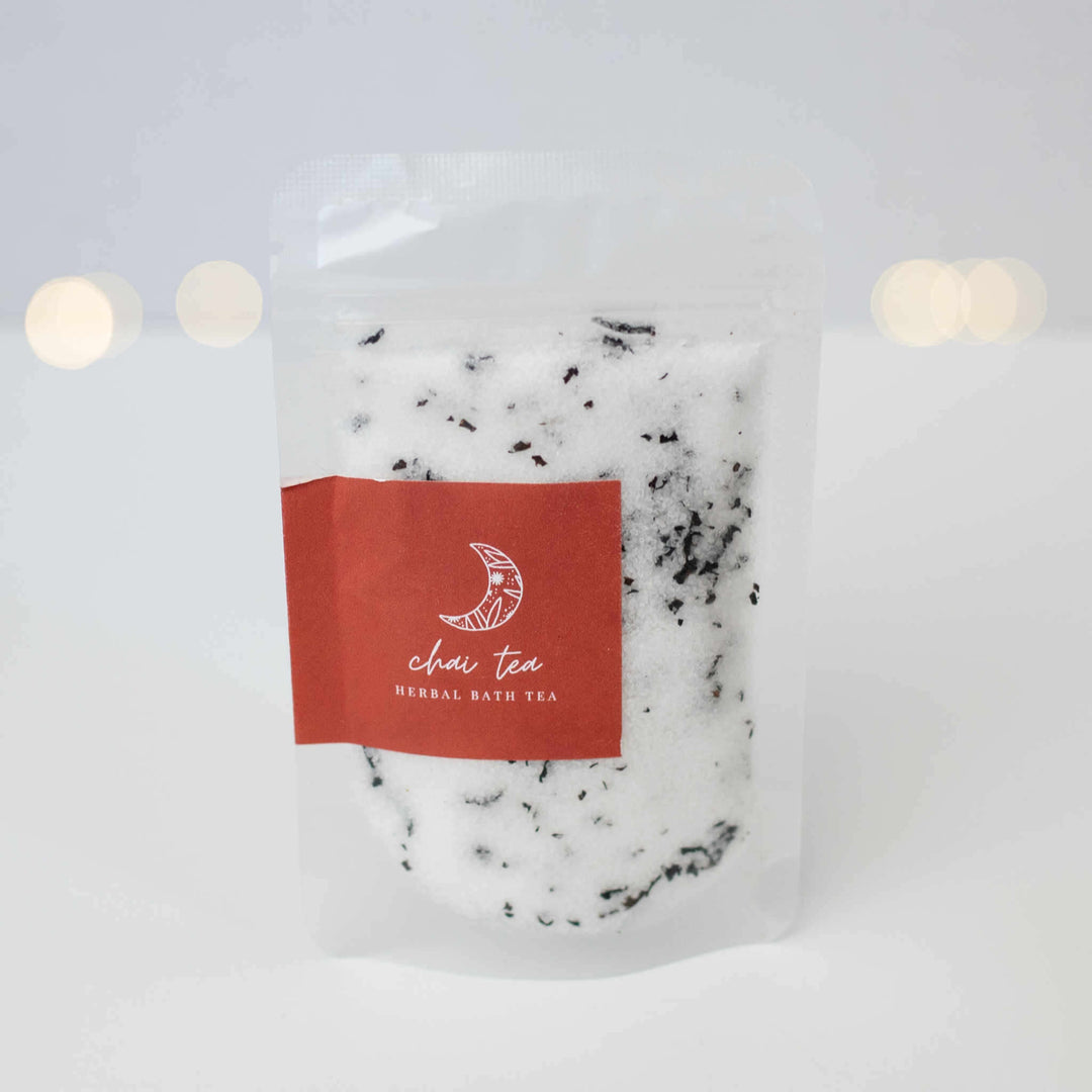 A transparent pouch filled with white herbal bath tea; red label says &