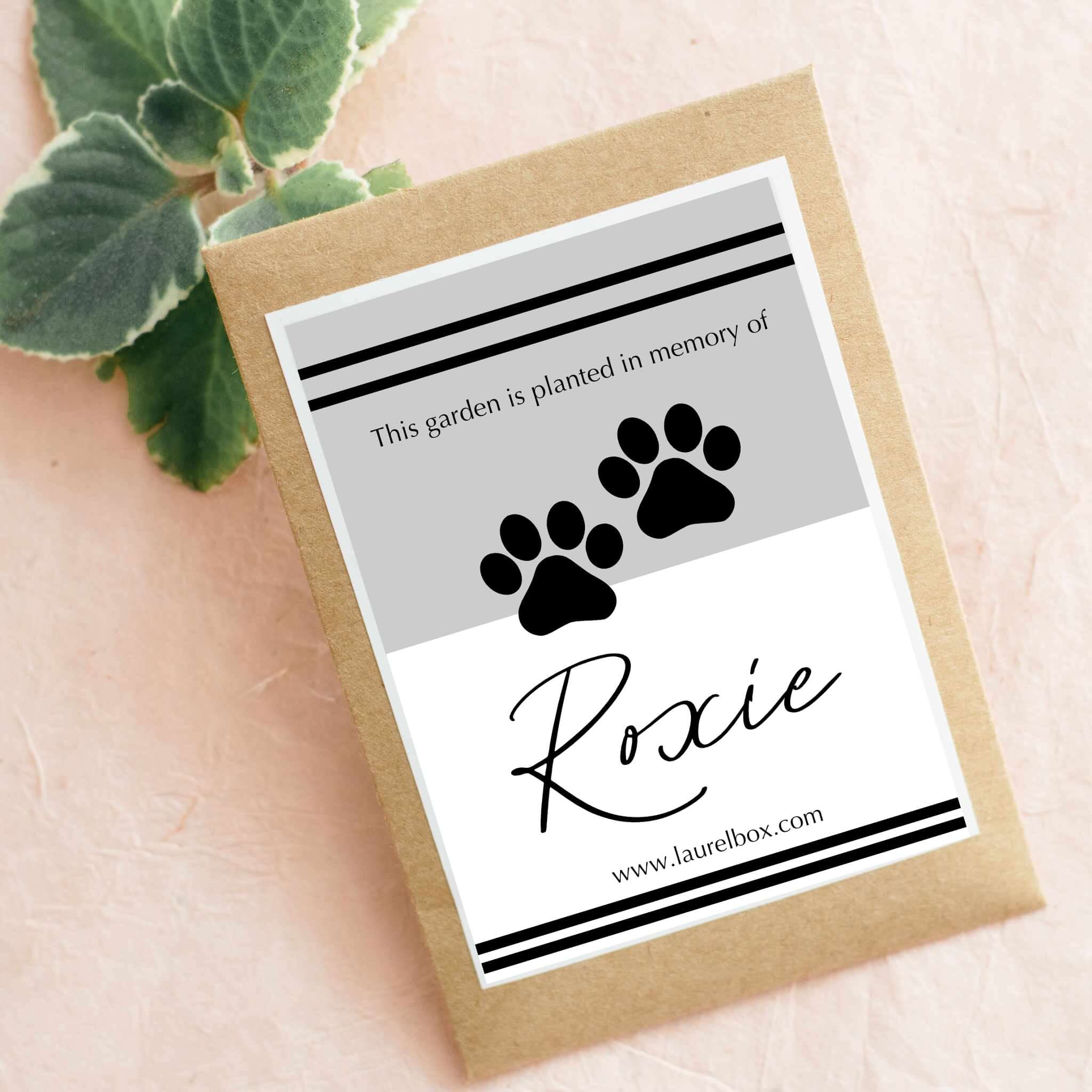 Pet Memorial Garden Set seed packet with paws and name 'Roxie' printed on a gray and white label.