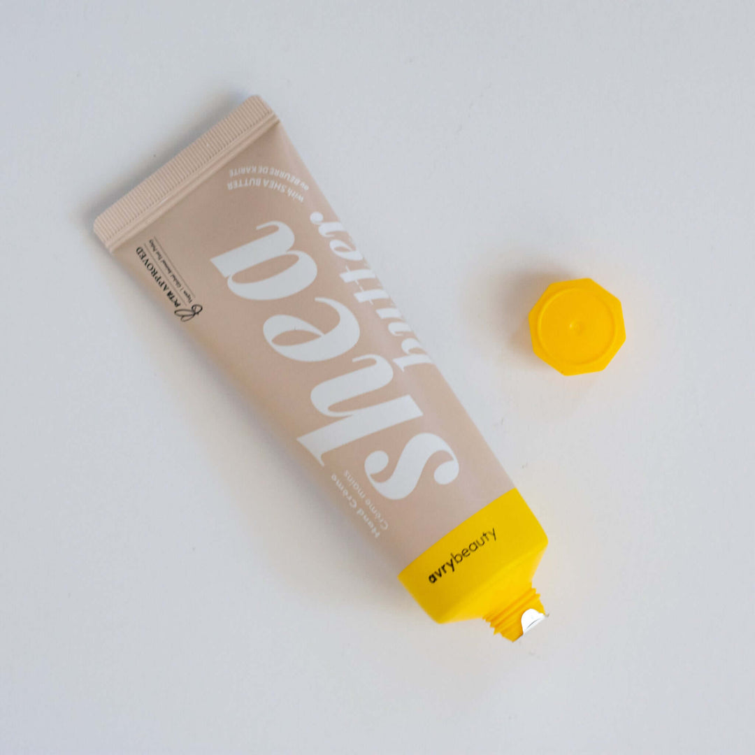 Shea Butter Hand Cream tube in light beige with white text, yellow cap, and opened top, set against a white background.