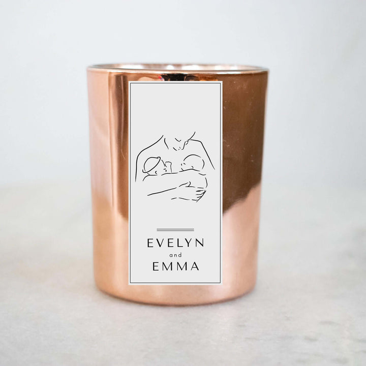 Twin Loss Memorial Candle in a rose gold holder with the names Evelyn and Emma on a white label, featuring a drawing of a parent holding twins.