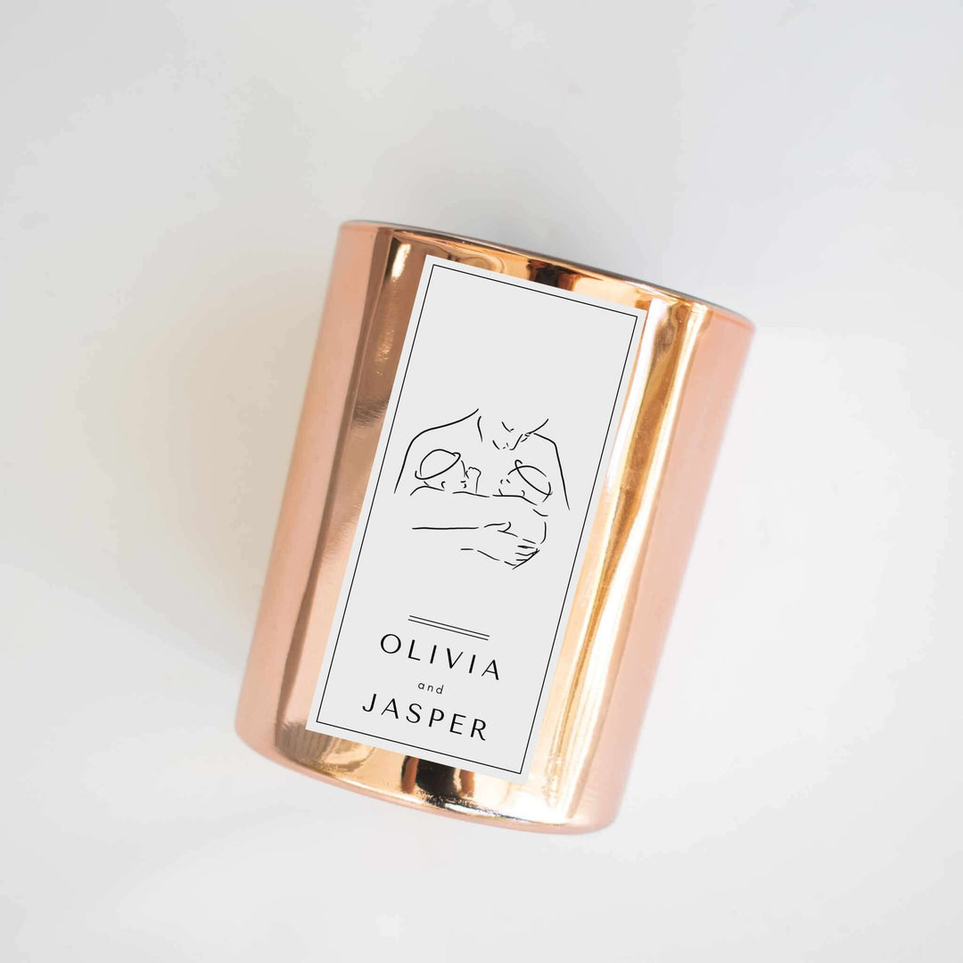 Twin Loss Memorial Candle in a rose gold container, featuring a label with illustrations of two babies and names Olivia and Jasper.