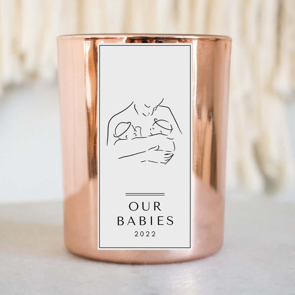 Twin Loss Memorial Candle with a copper holder and a label featuring a drawing of a parent holding twins. Text: OUR BABIES 2022.